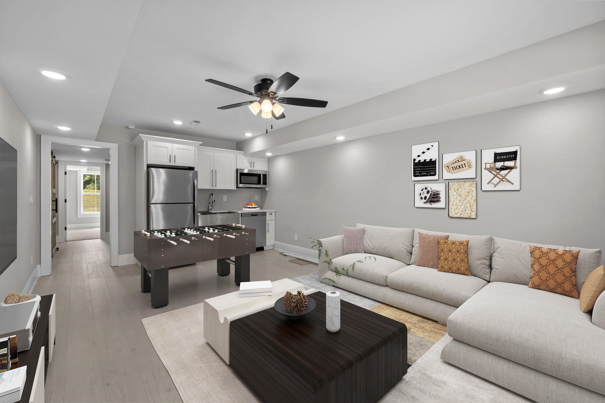 Staged living room with kitchenette, foosball table, and light sectional sofa.