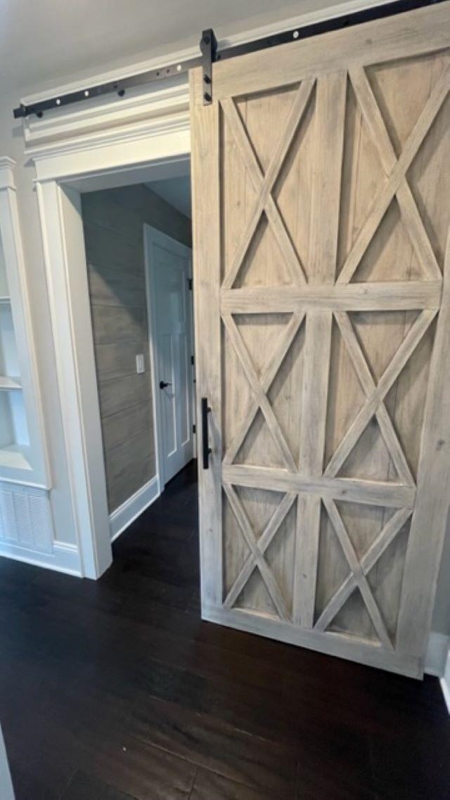 Hallway with a geometric-braced wood sliding barn door and an open doorway.