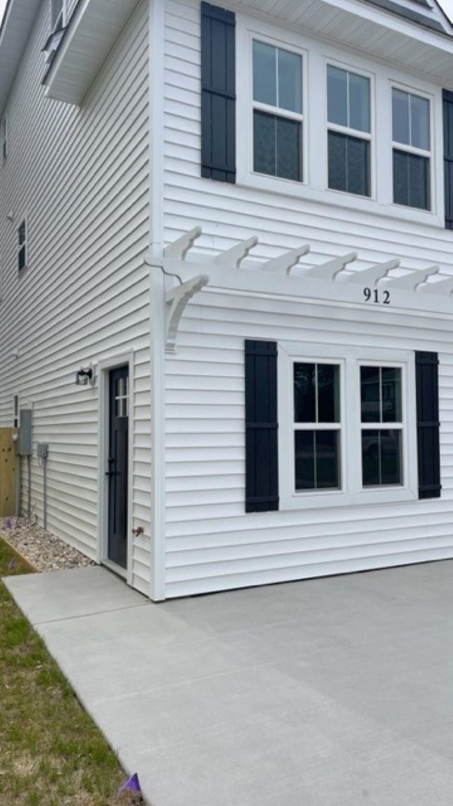 White two-story house with dark shutters, a side entry, and a broad concrete driveway.