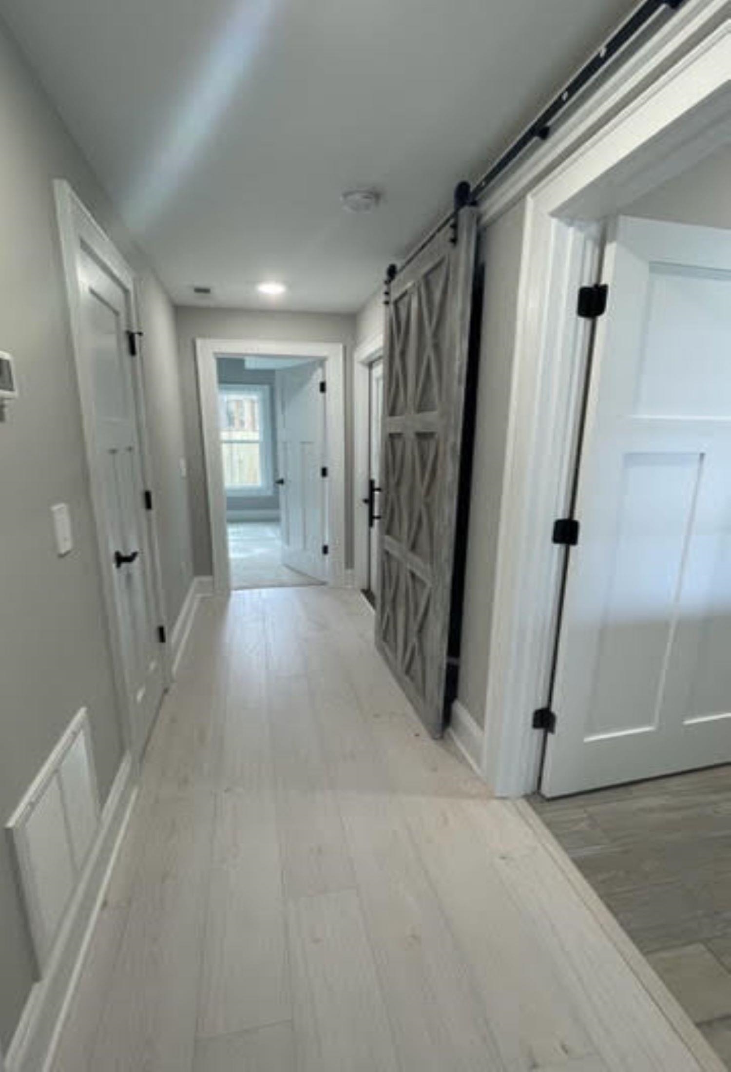 Hallway with light plank flooring and an open gray barn-style sliding door.