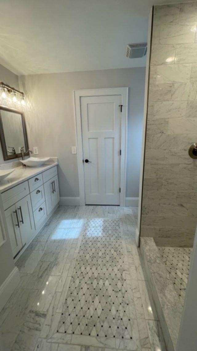 Bathroom with a white vanity, marble-look floors, patterned mosaic runner, and tiled walk-in shower.