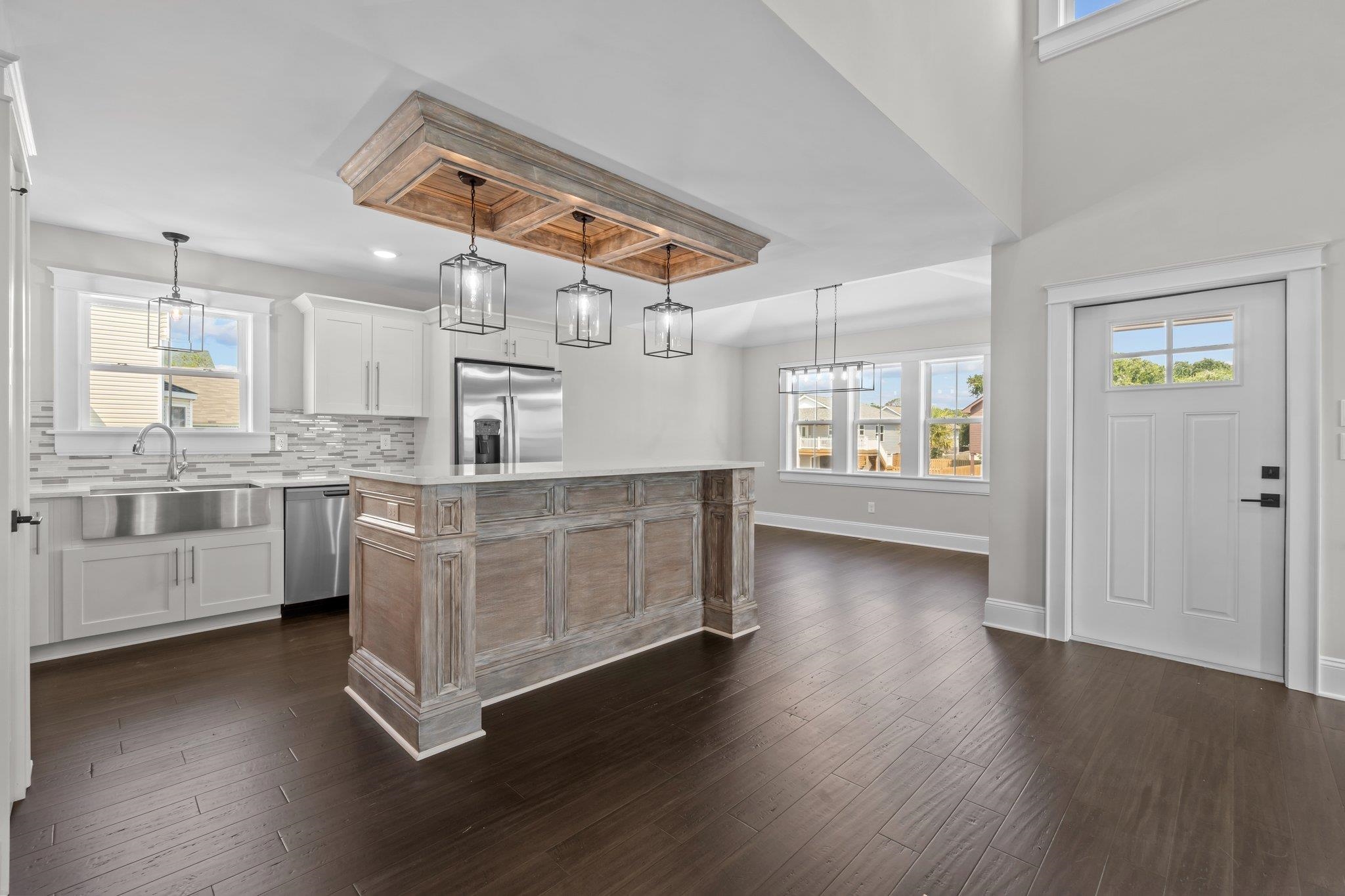 Kitchen with a large weathered-wood island, white cabinets, stainless steel appliances, and dark hardwood floors.