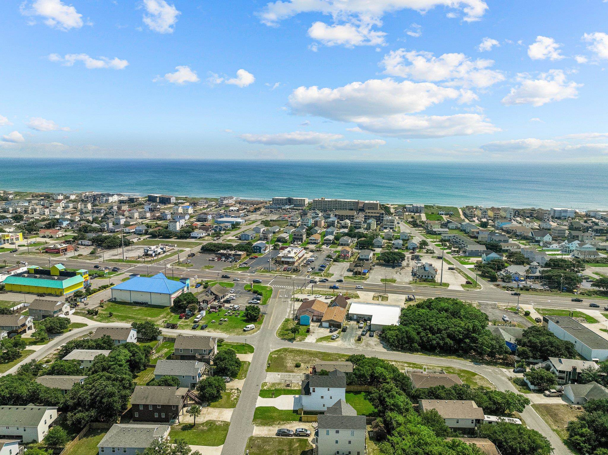 Aerial coastal neighborhood with homes and streets leading toward the ocean.