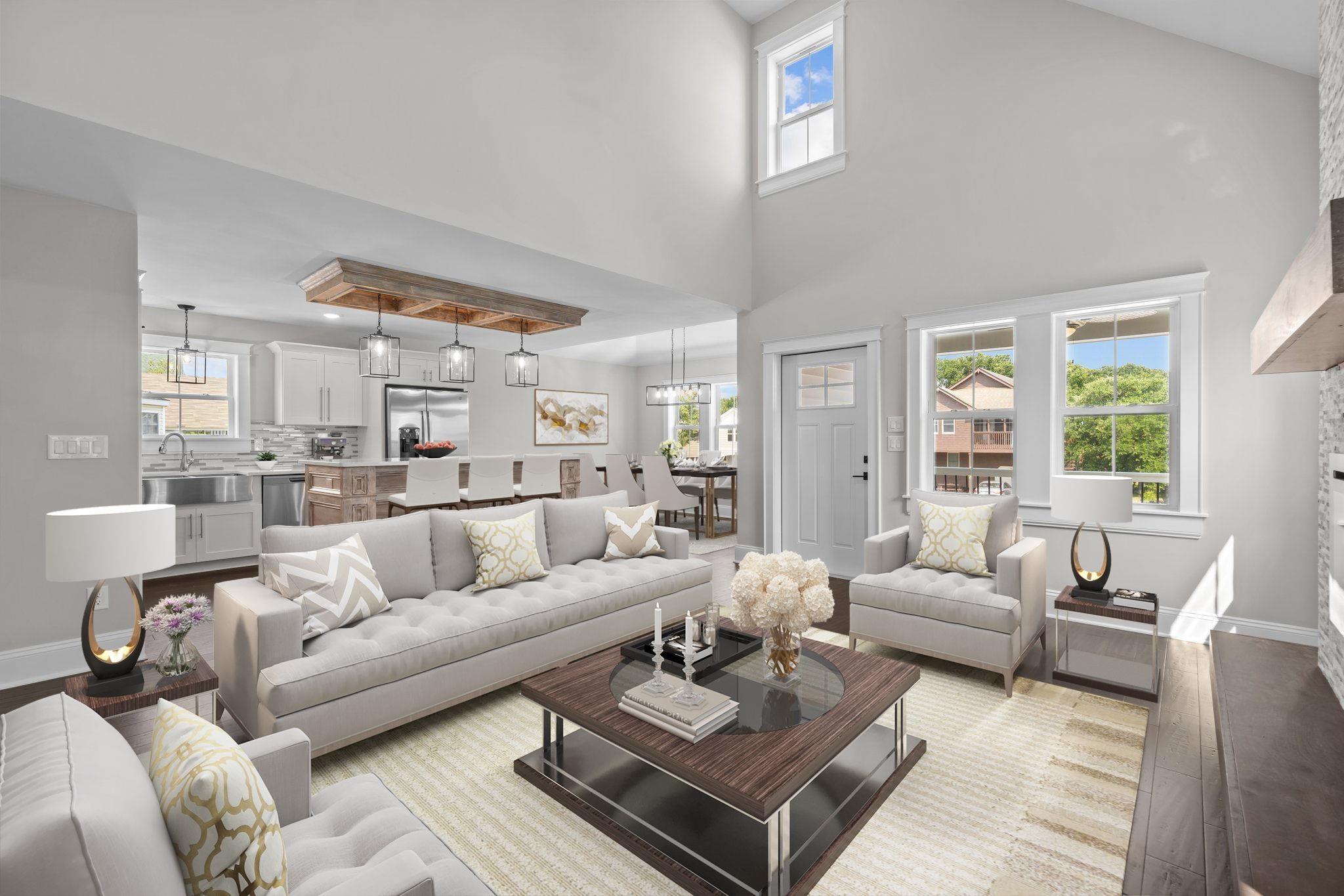Open-plan living room with a gray sectional, vaulted ceiling, and adjoining kitchen.