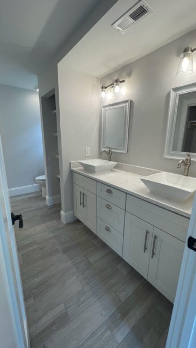 Bathroom with a long white double-sink vanity, framed mirrors, and gray tile flooring.