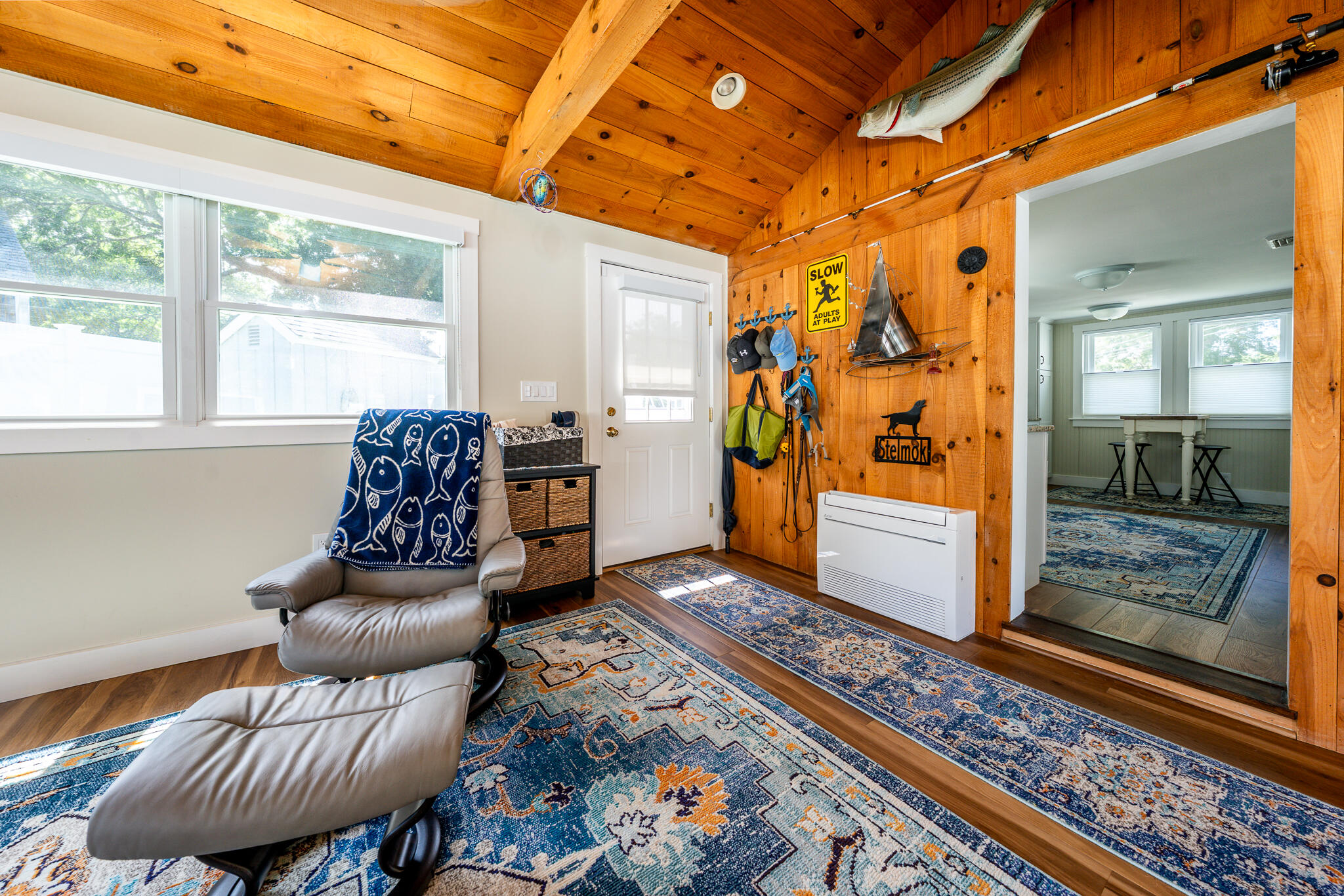 Furnished room with a vaulted wood ceiling, leather lounge chair, patterned rugs, and fishing decor.