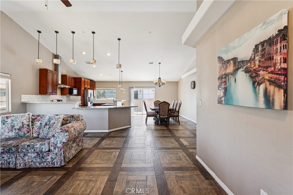 Open-plan living, dining, and kitchen area with dark cabinetry, a peninsula island, and patterned tile floors.