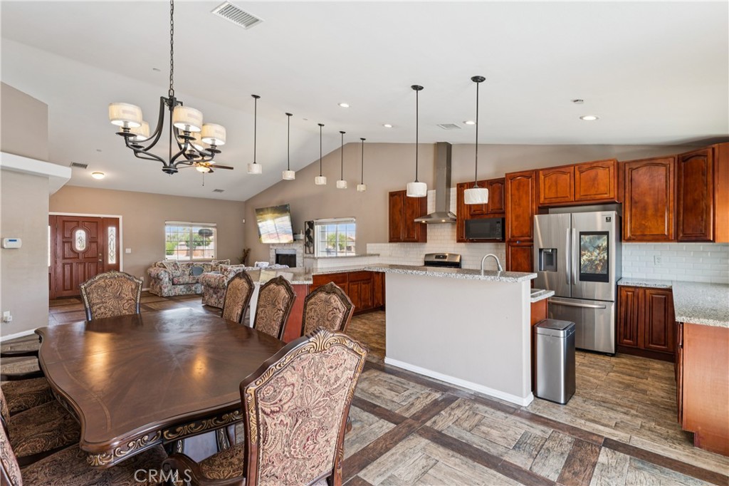 Open-plan kitchen and dining area with dark wood cabinets, stainless steel appliances, and a large dining table.
