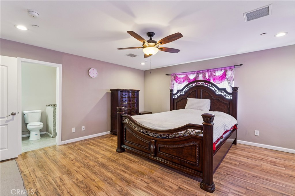 Bedroom with a carved dark wood bed, pink curtains, and an open doorway to a bathroom.