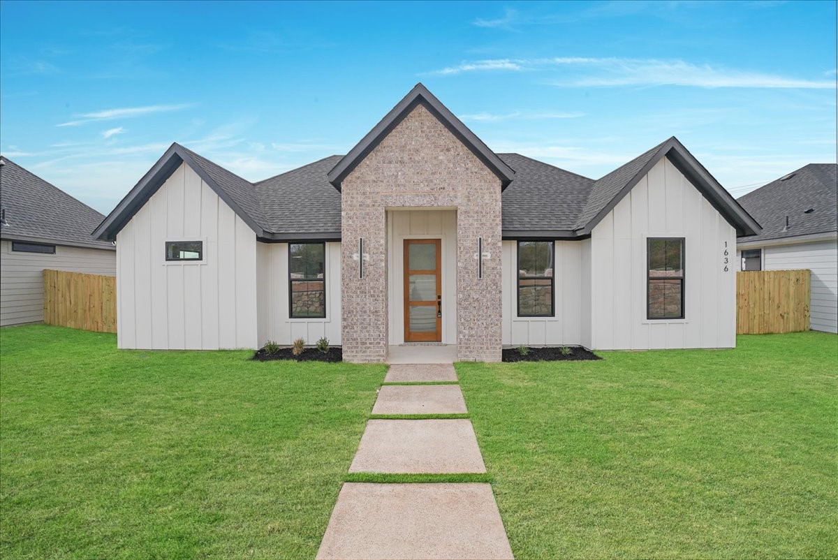 Single-story home with white siding, a brick entry, and a concrete walkway across a green lawn.