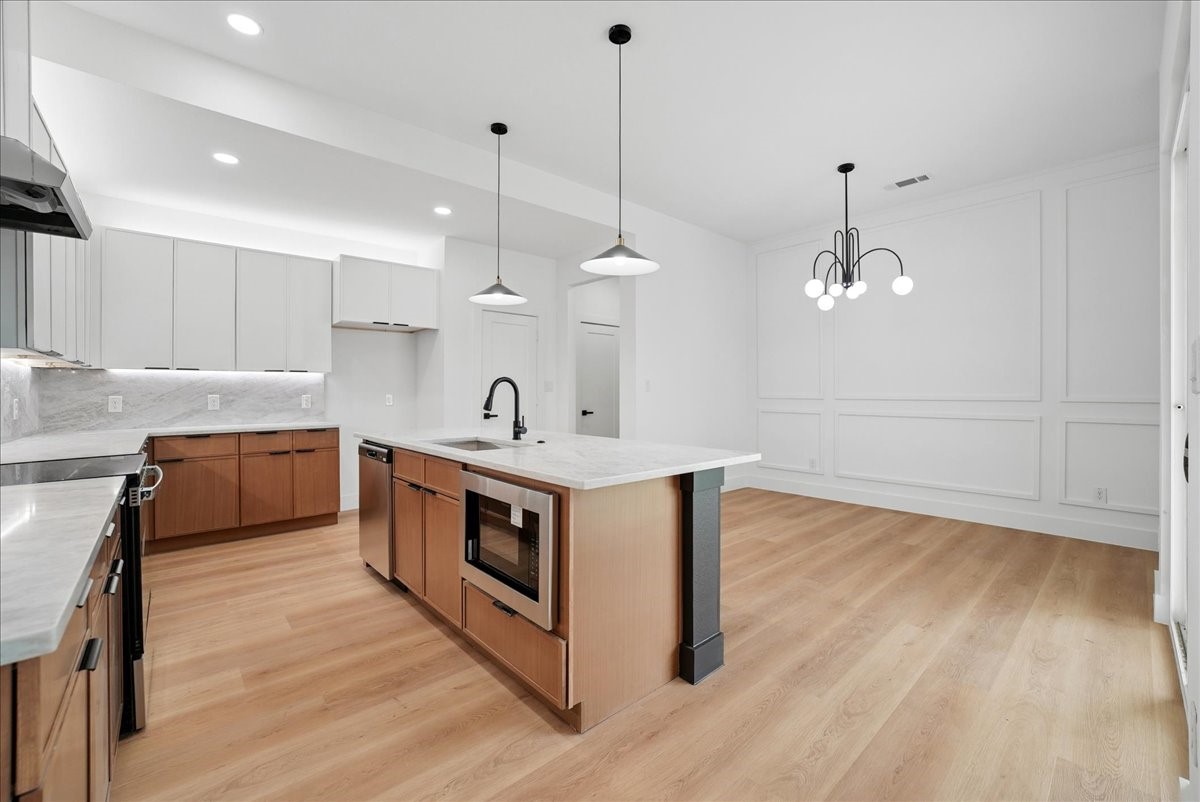 Modern kitchen with a large wood-sided island, white cabinets, and light wood floors.