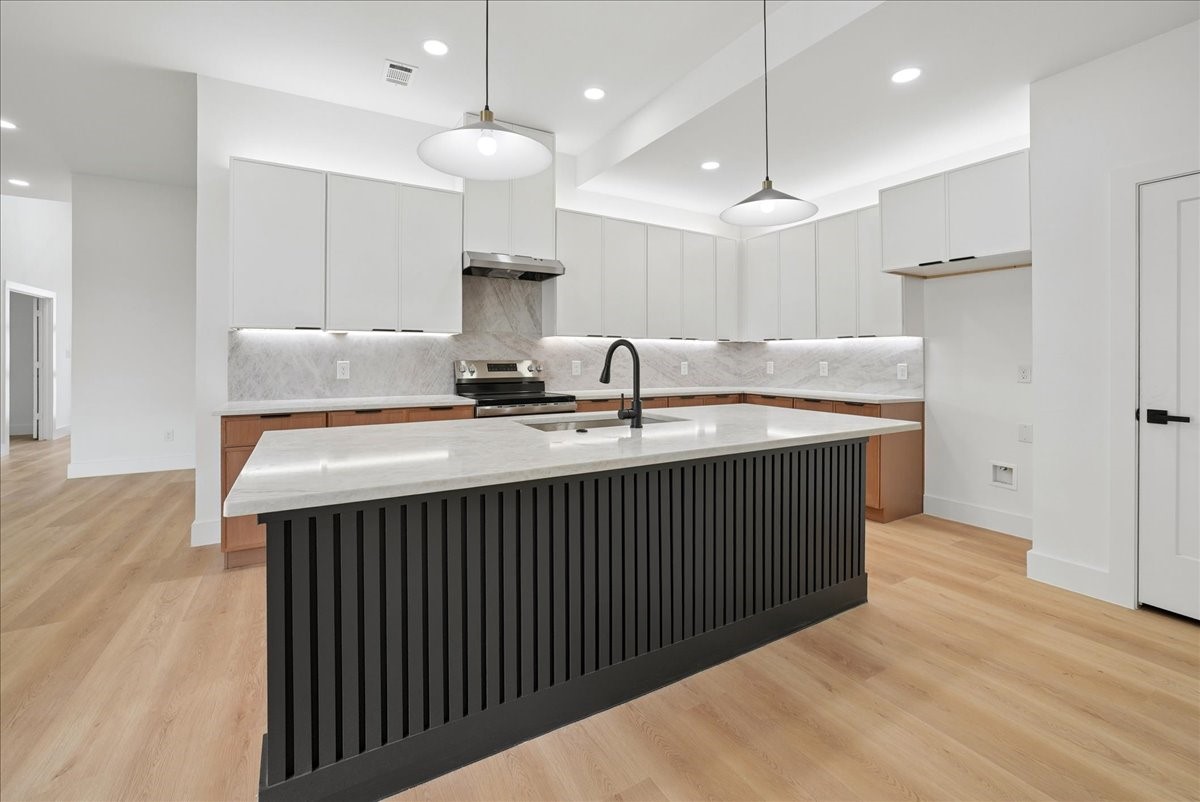 Modern kitchen with a large black fluted island, white countertop, and white cabinetry.