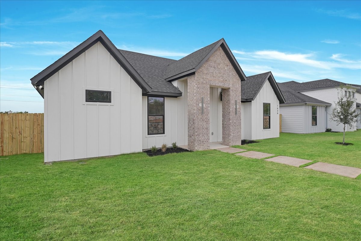 Modern white-sided home with a brick entry, gabled rooflines, and a broad green lawn.