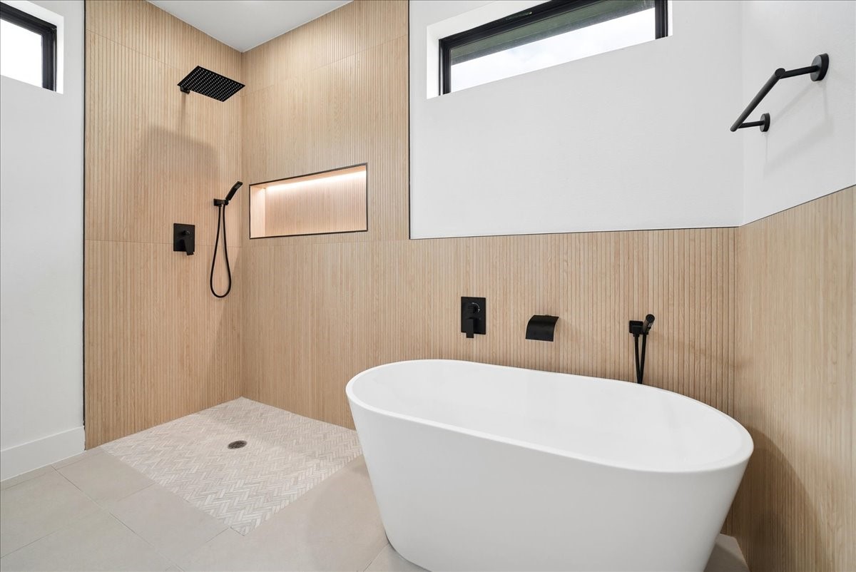 Modern bathroom with a freestanding tub, walk-in shower, and light wood-look tile.
