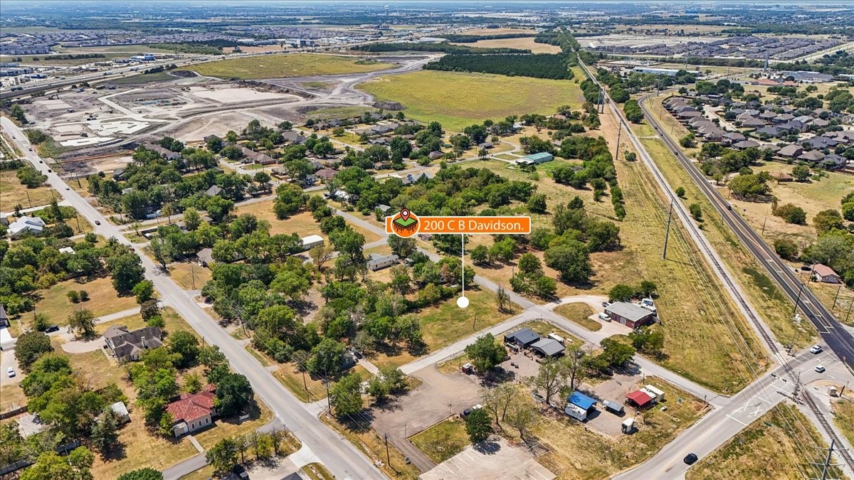 Aerial view of the property marked by an orange location pin, surrounded by homes, roads, and open land.