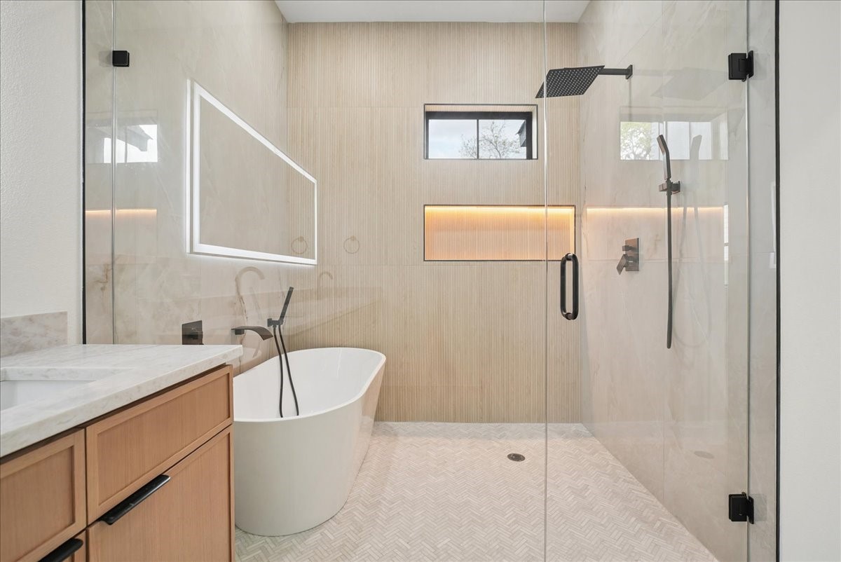 Modern bathroom with a glass walk-in shower, freestanding tub, and wood vanity.