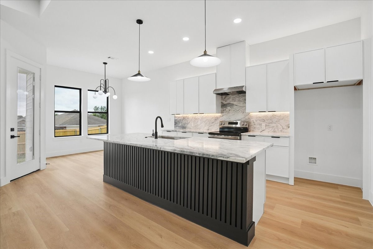 Modern kitchen with a large black fluted island, white cabinetry, and marble-pattern counters.