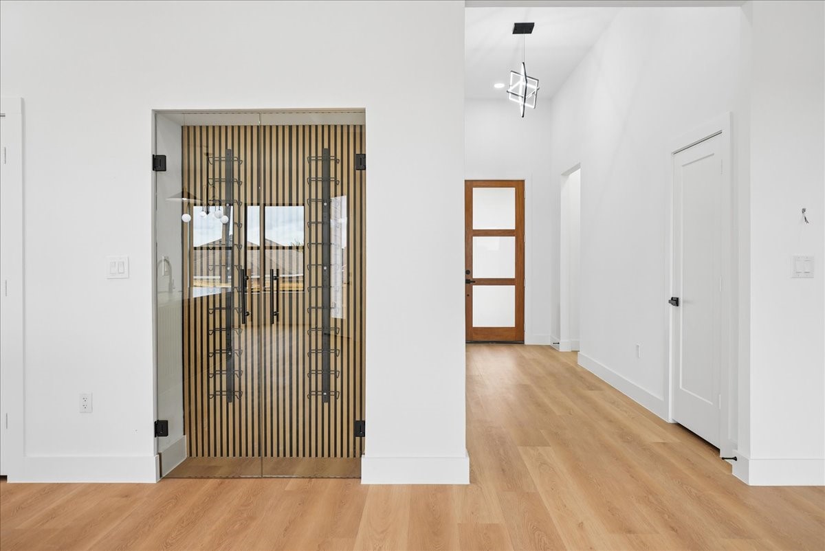 Entry foyer with wood flooring and distinctive glass double doors with vertical wood slats.