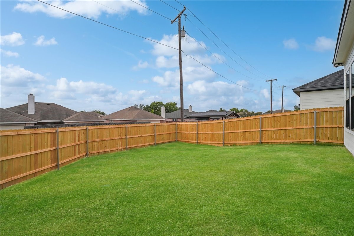 Backyard with a broad green lawn and tall wooden privacy fence.