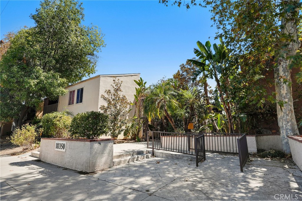 Commercial building at 18350 behind a metal gate, framed by mature trees and tropical landscaping.