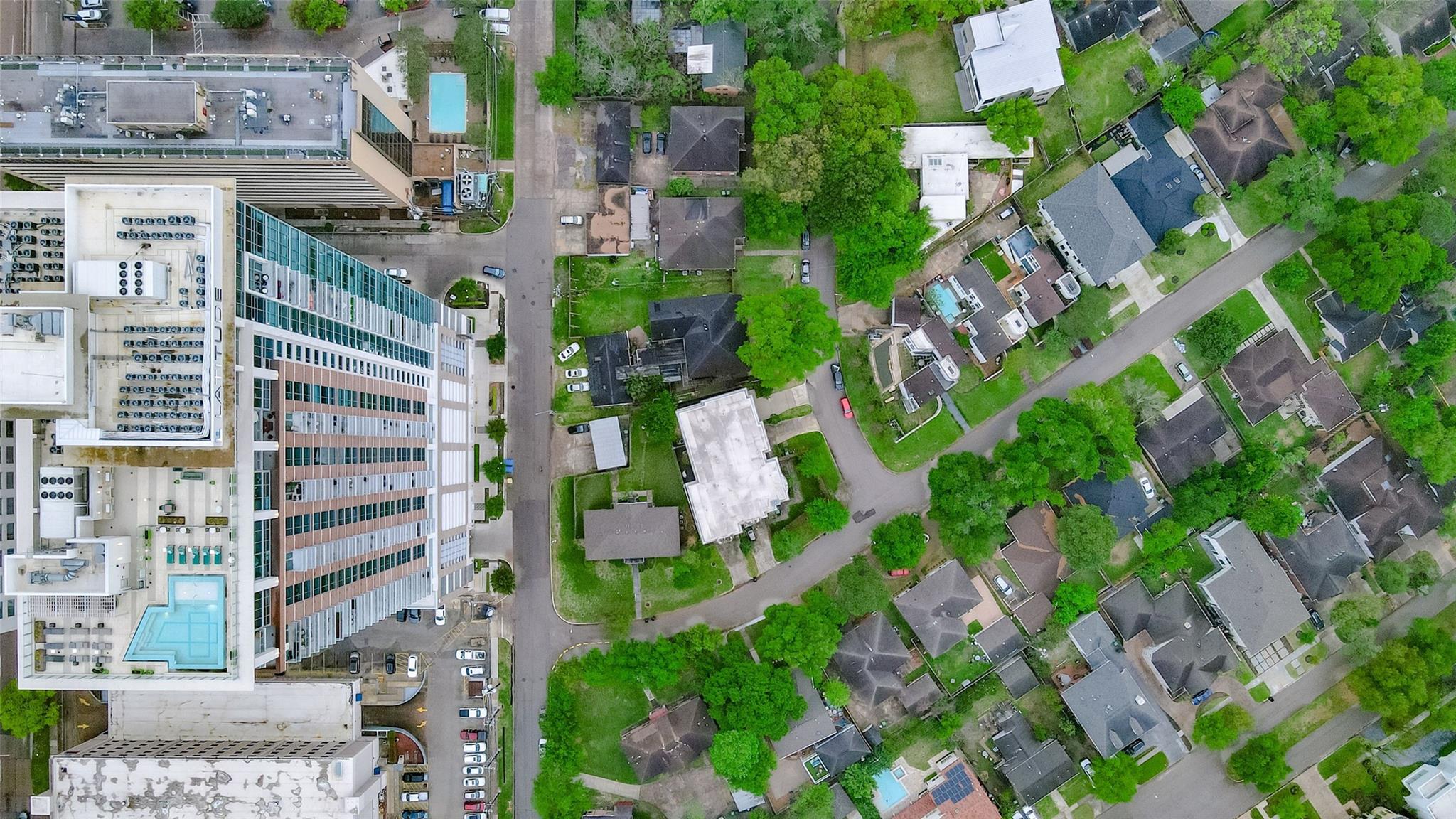 Aerial view of homes and tree-lined streets beside a large multi-story building.