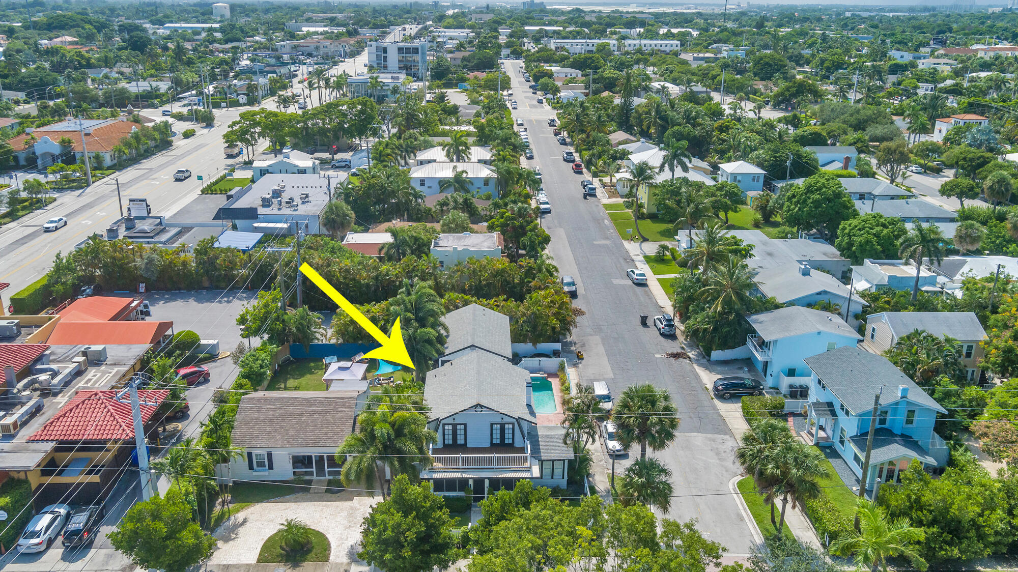 Aerial view of a house and pool marked by an arrow in a palm-lined neighborhood.