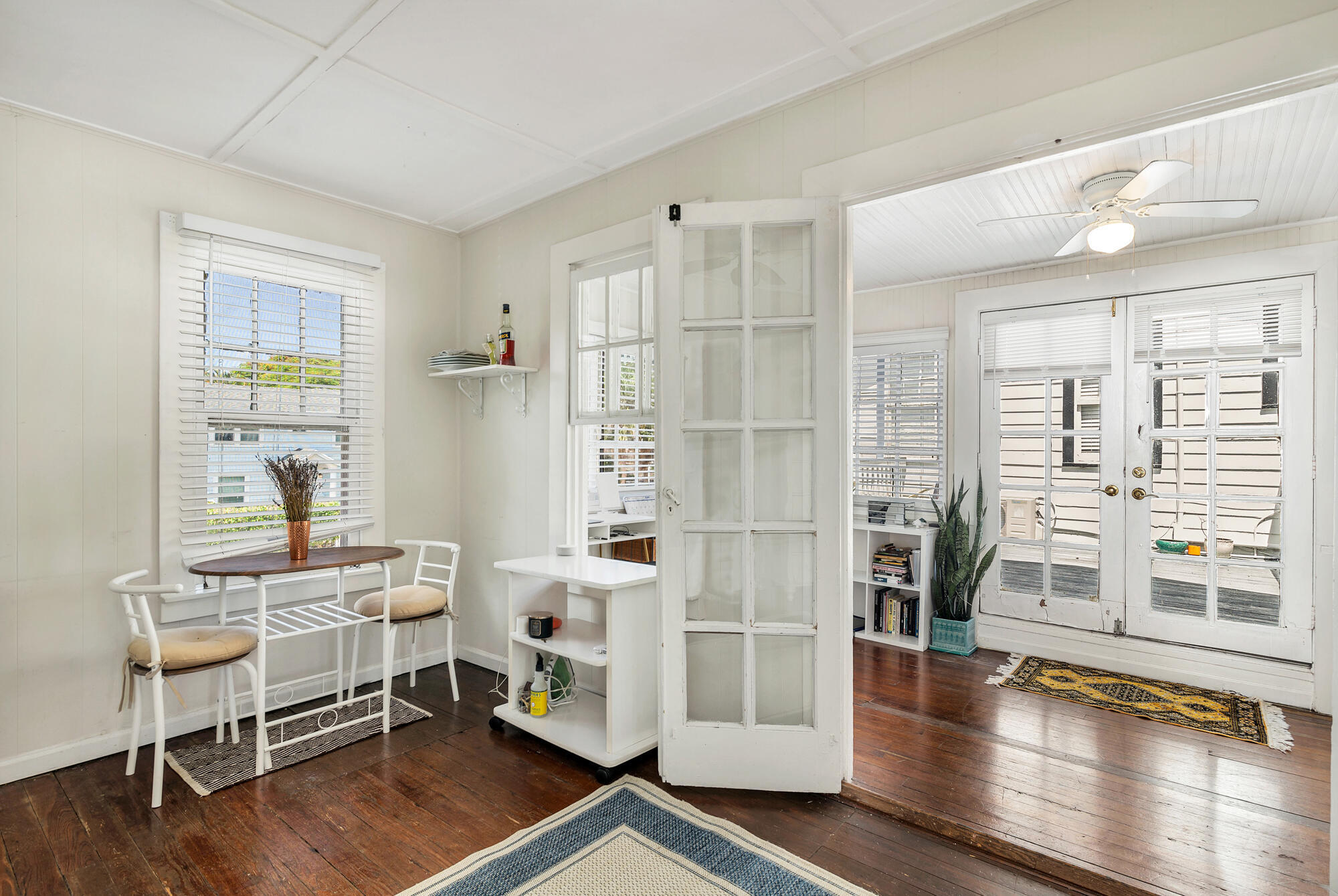 Dining area with a small table, hardwood floors, and glass-paneled doors.