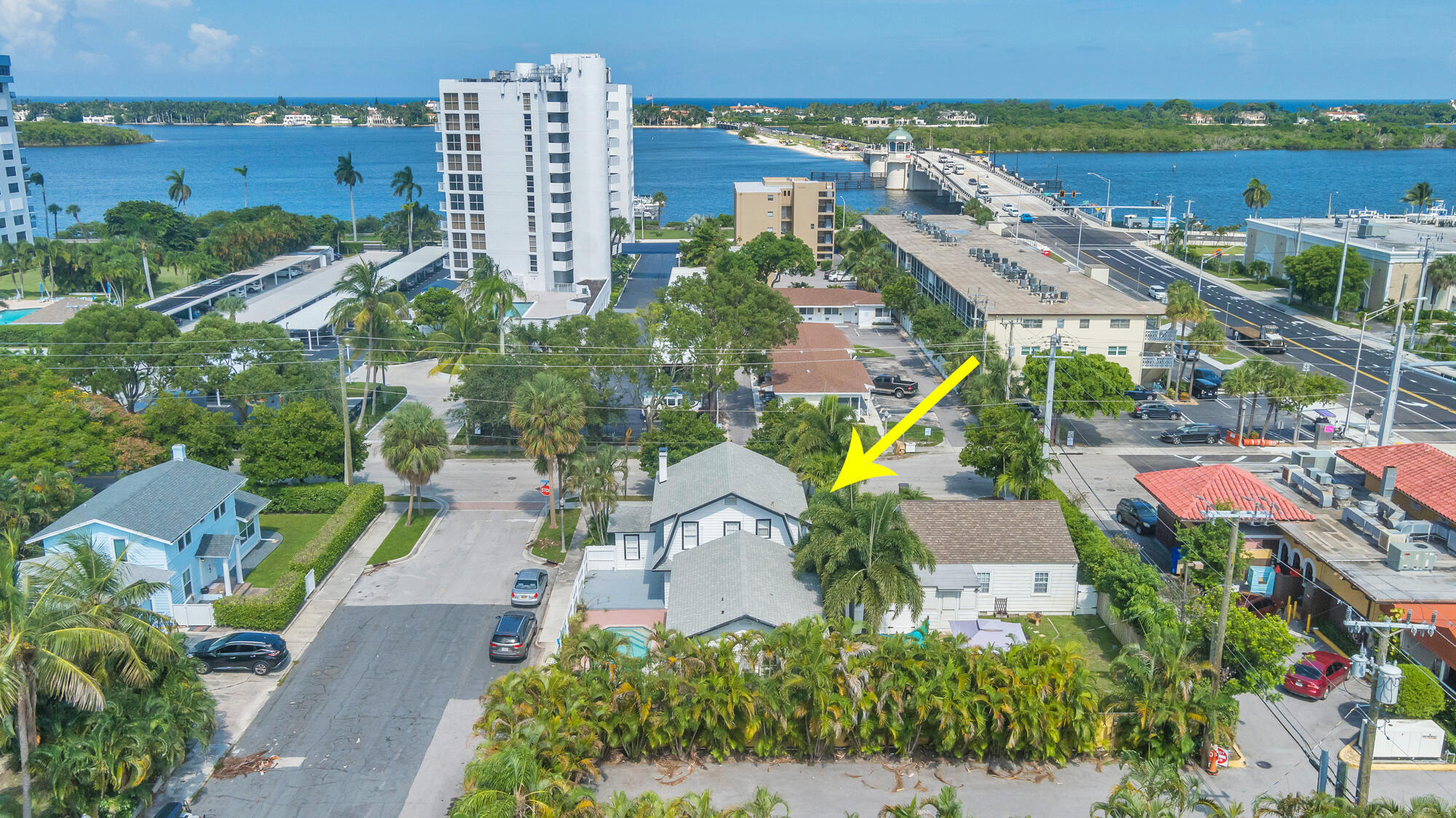 Aerial view of the arrow-marked home among palm trees, with the Intracoastal Waterway and bridge beyond.