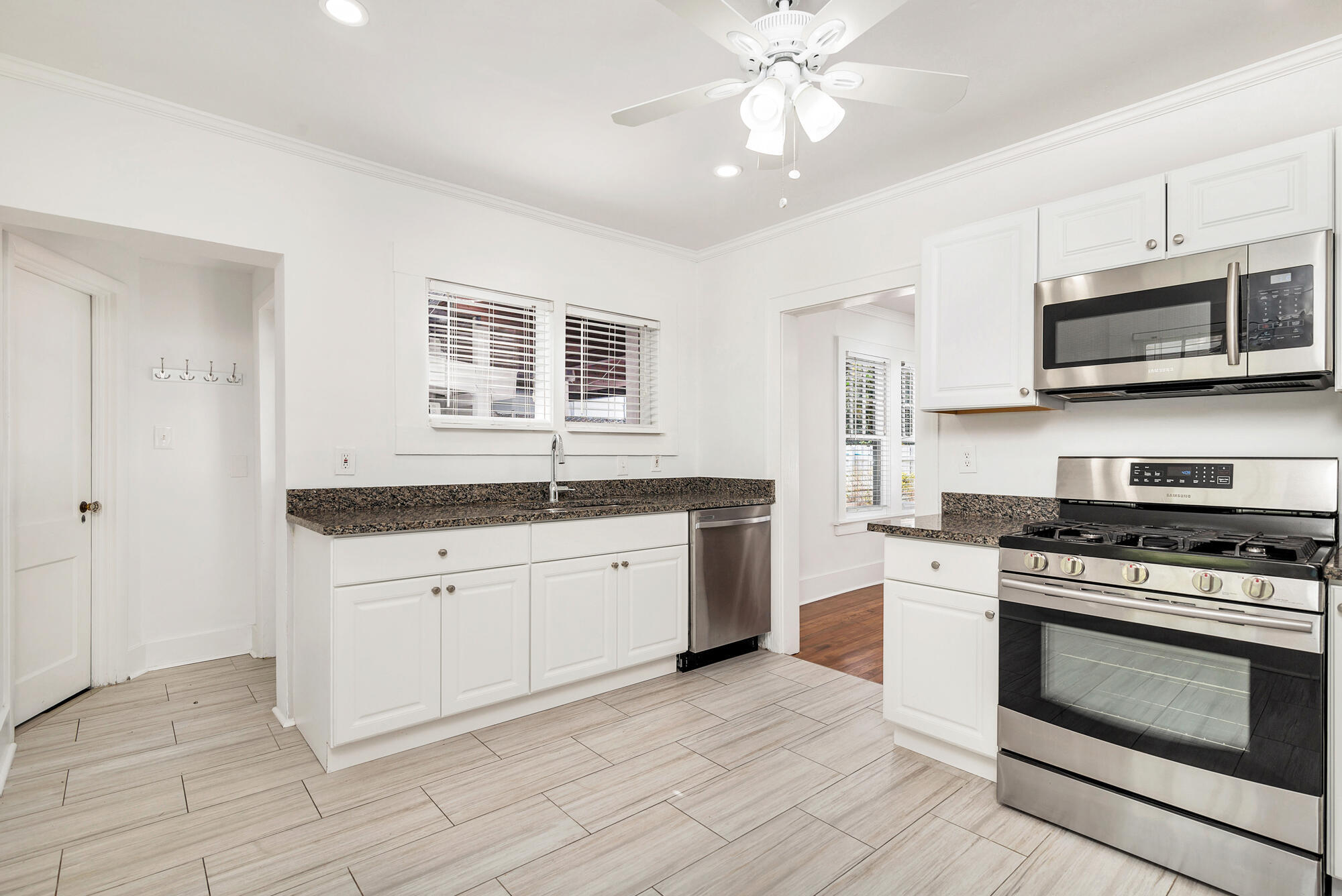 Kitchen with white cabinets, granite counters, stainless steel appliances, and light tile flooring.