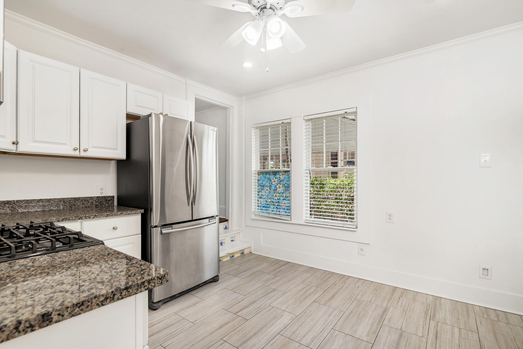 Kitchen with white cabinets, granite counters, and stainless steel appliances beside two windows.