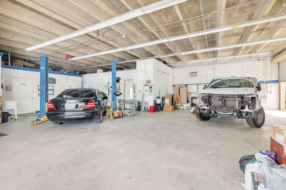 Automotive workshop with two vehicle lifts, a black sedan, and a partially disassembled vehicle.