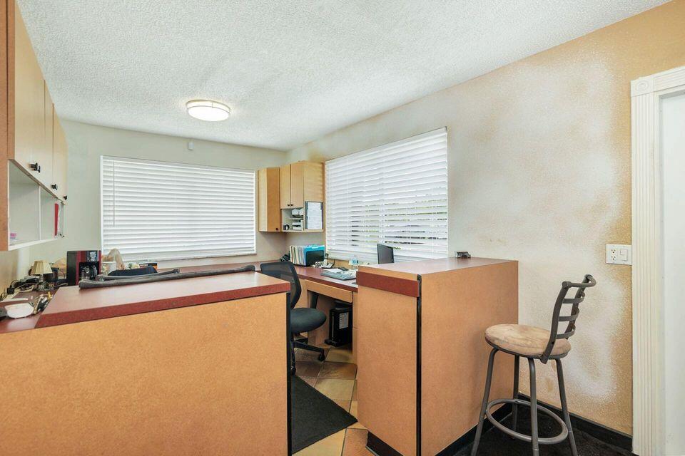Office reception area with tan counters, a desk, and windows fitted with white blinds.