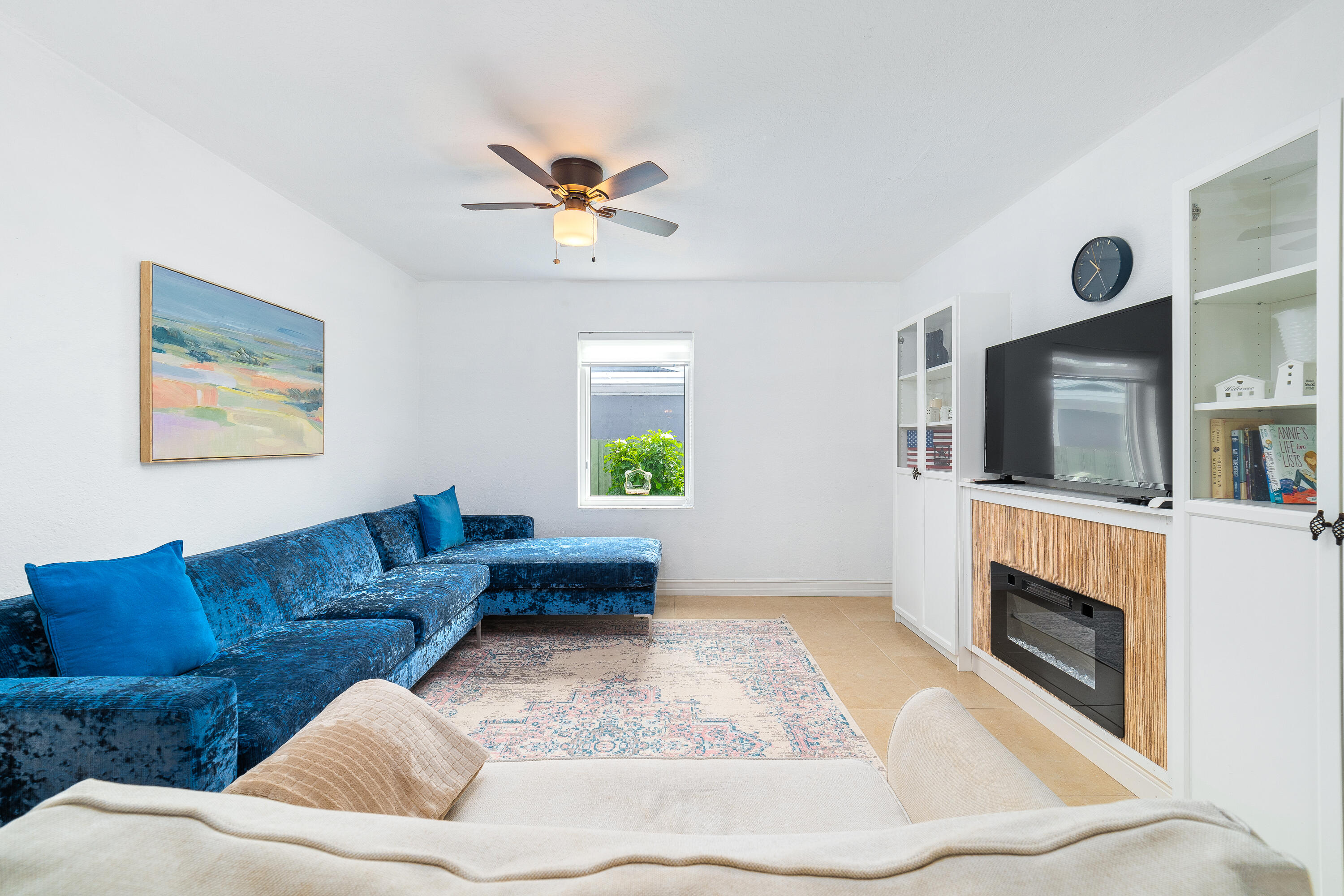 Living room with a blue sectional, built-in shelving, and a wood-paneled fireplace surround.