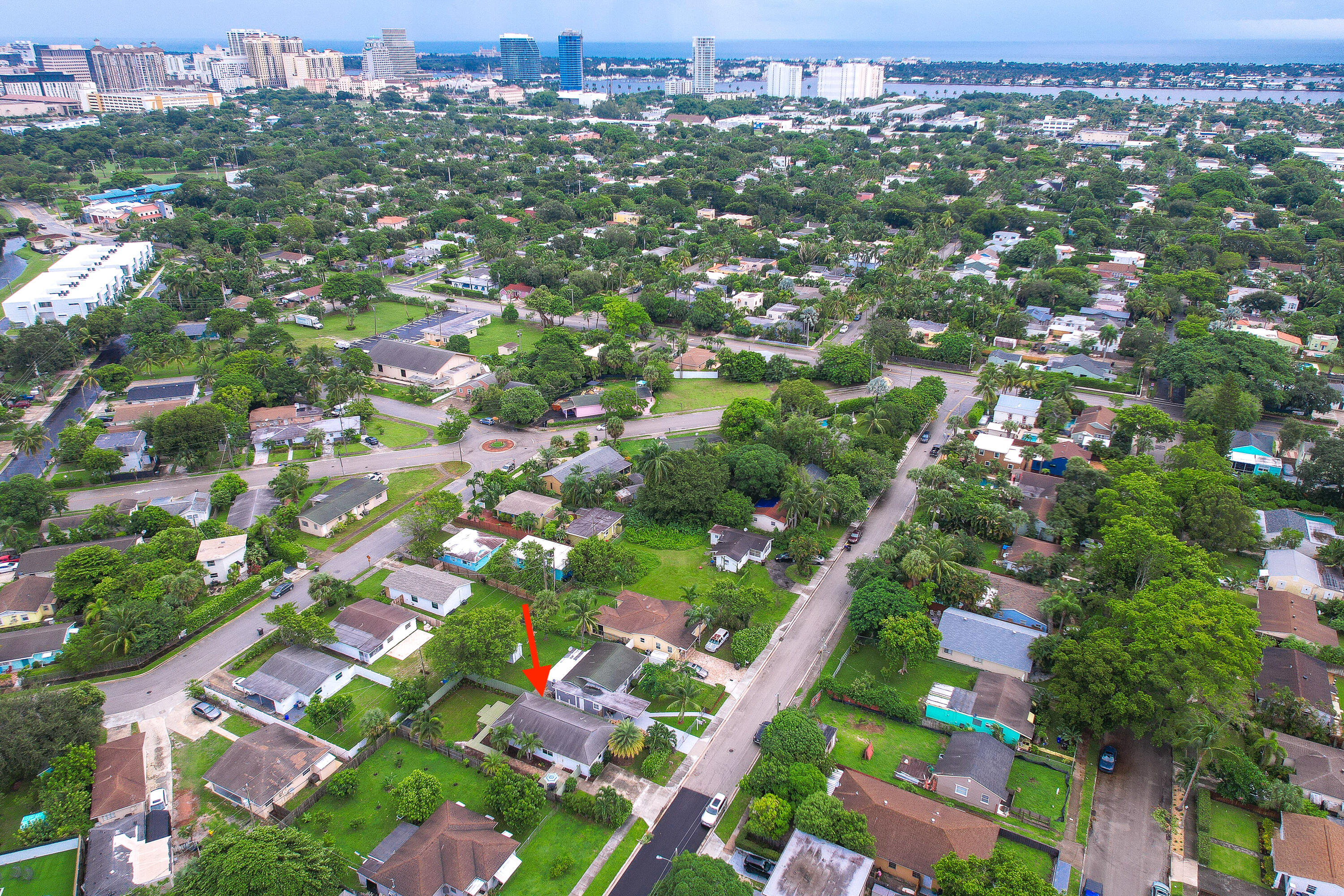 Aerial view of the marked home among tree-lined streets, with downtown West Palm Beach and the waterway beyond.