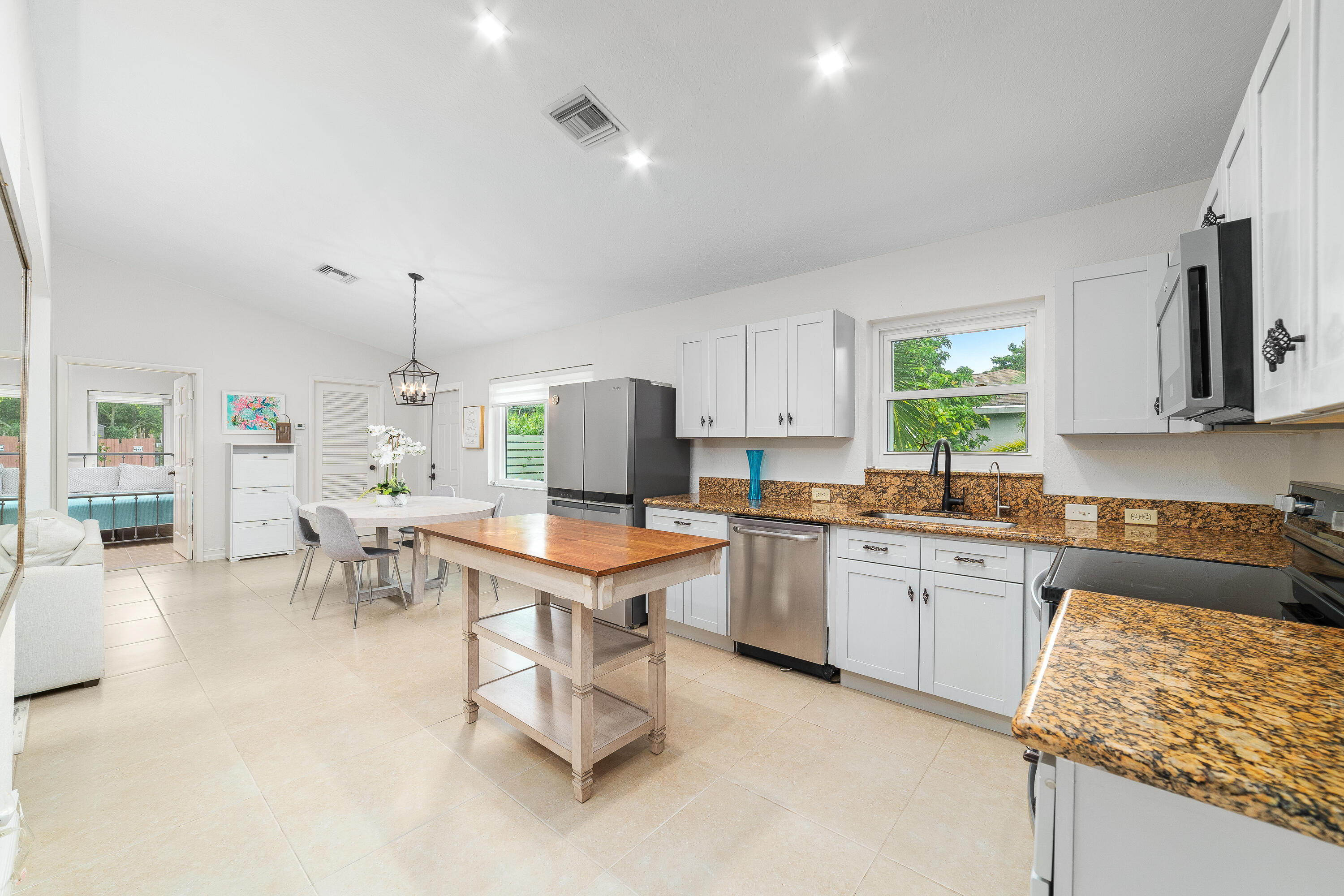 Kitchen with white cabinets, granite counters, stainless appliances, and a central wood-top worktable.