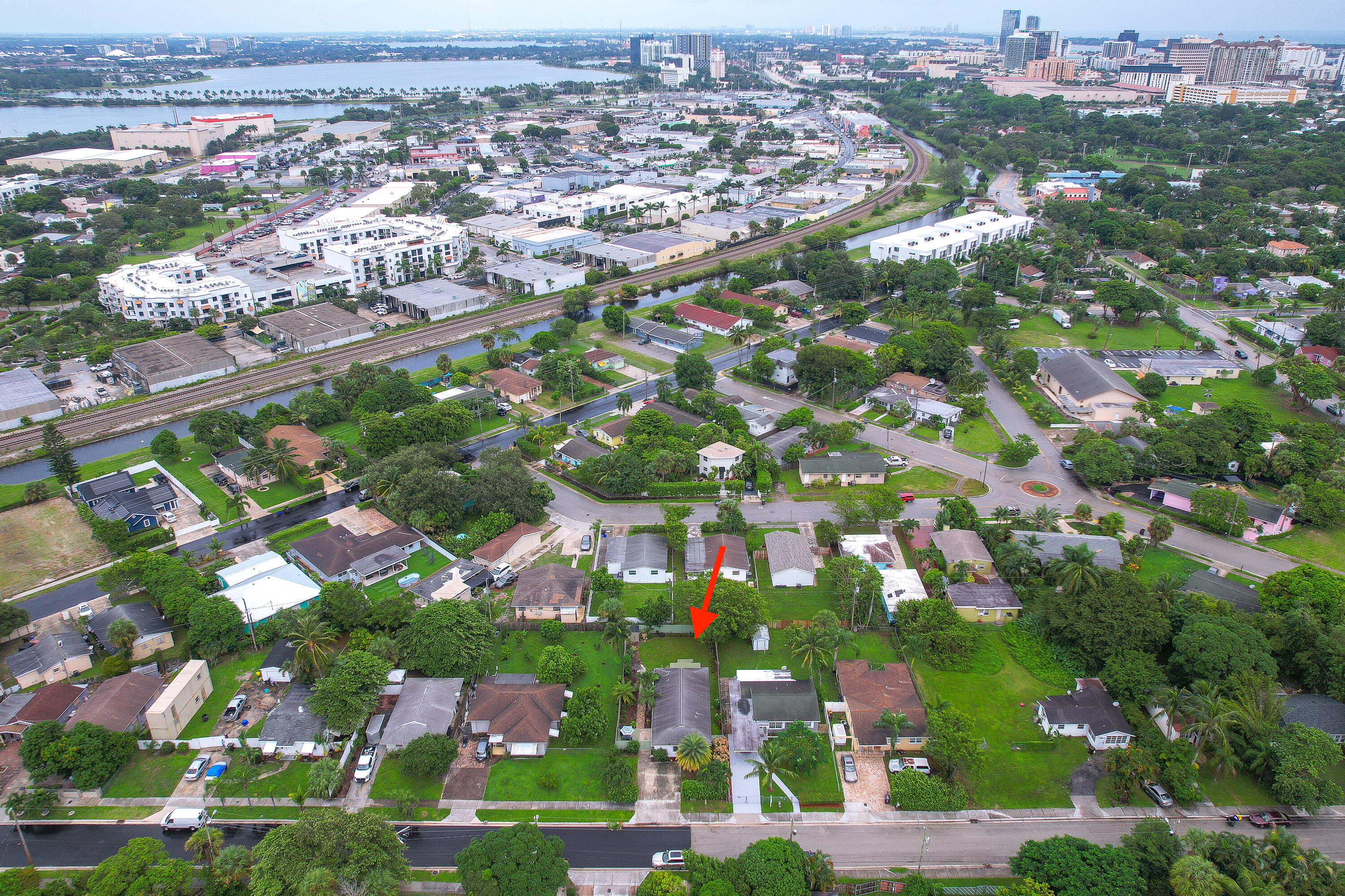 Aerial neighborhood view with a red arrow marking 949 Charles Street, canal and West Palm Beach skyline beyond.