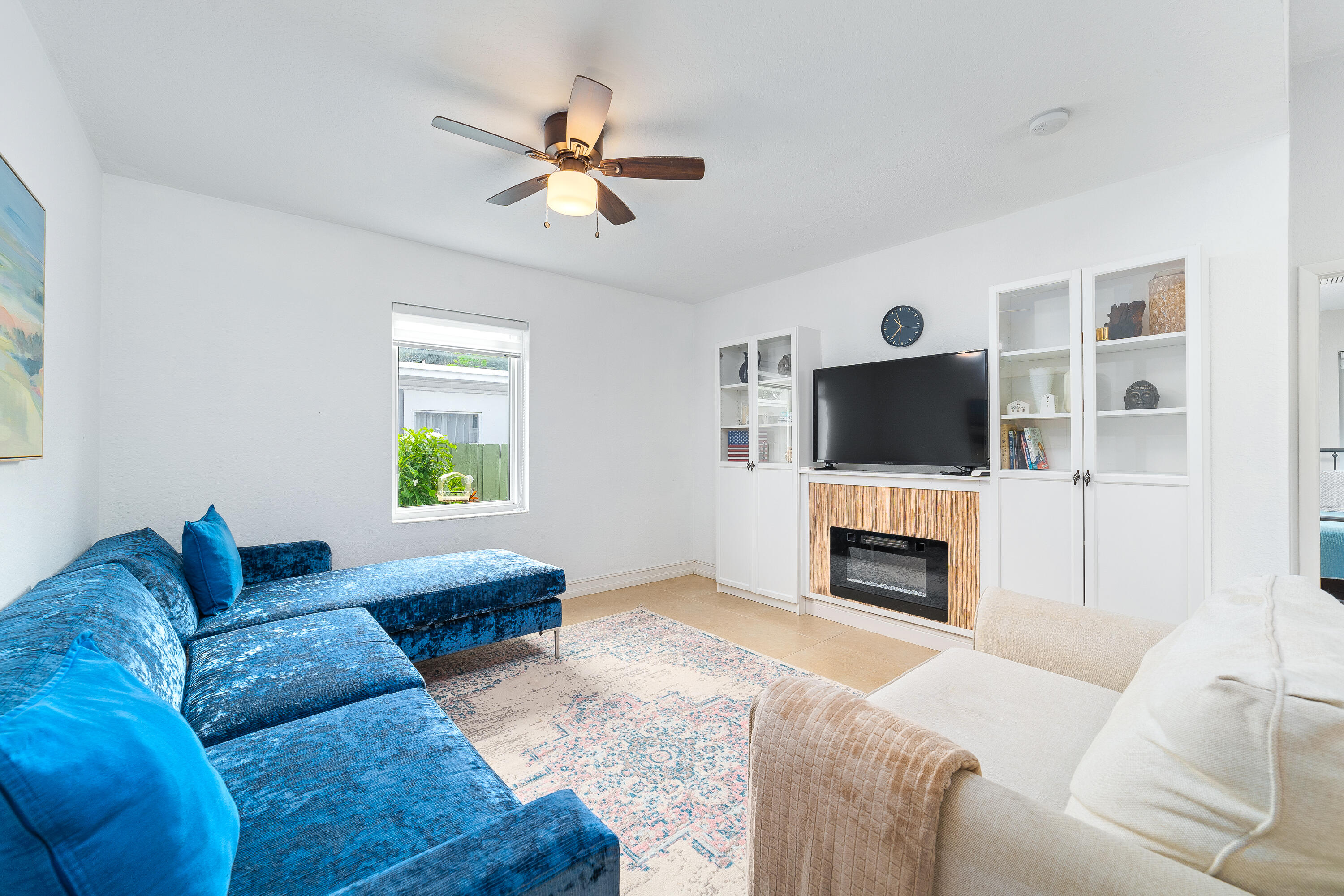 Living room with a blue sectional, white armchair, and built-in TV and fireplace cabinetry.