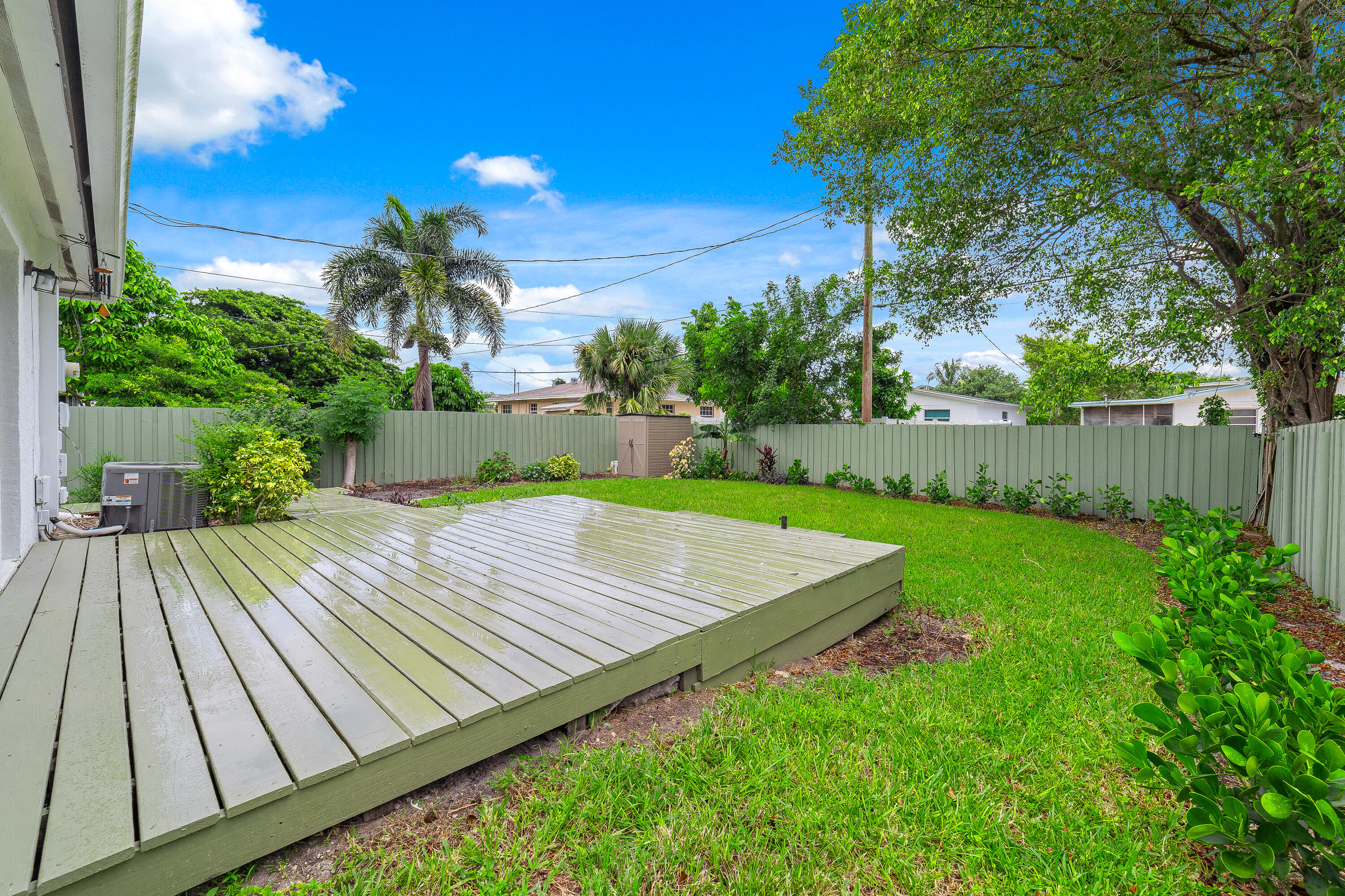 Backyard with a raised wooden deck, green lawn, and tall privacy fence.