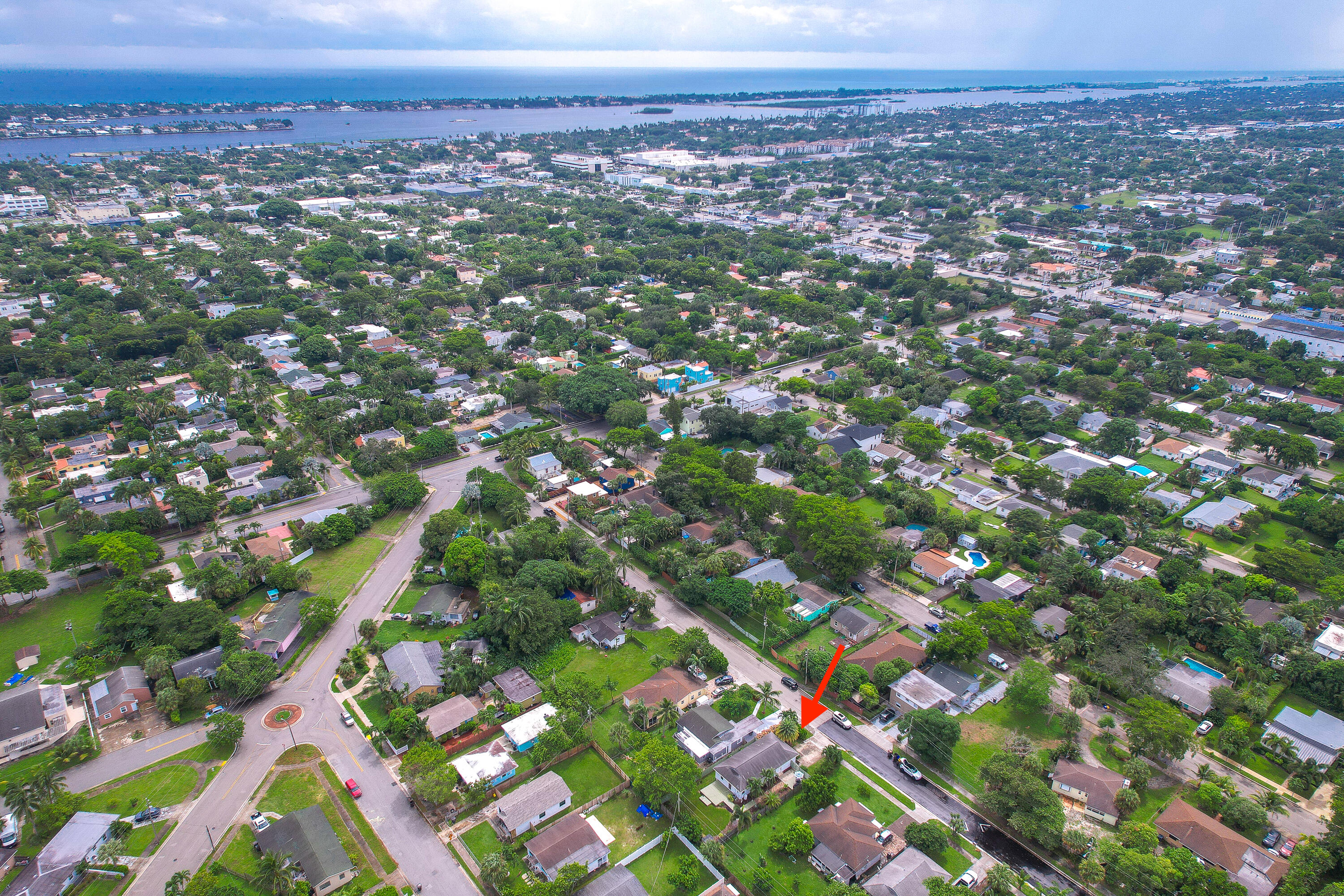 Aerial view of the arrow-marked home amid a leafy neighborhood near the water.