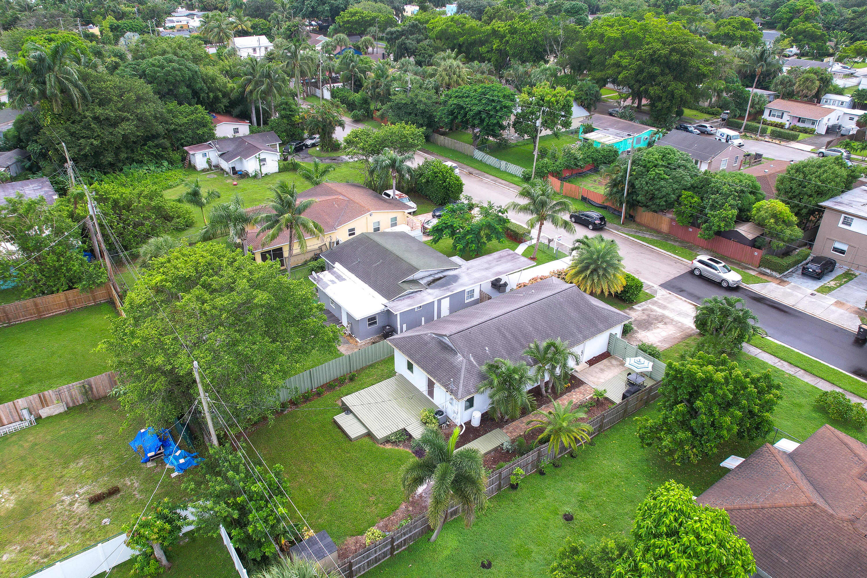 Aerial view of a single-story home with a landscaped yard, palm trees, and a small deck.