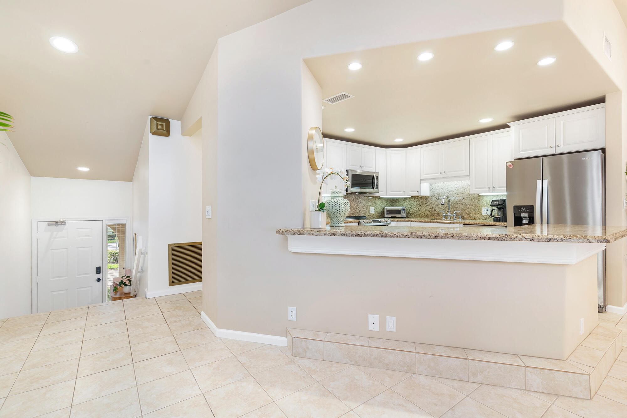 Kitchen with white cabinets, granite counters, stainless steel appliances, and a raised breakfast bar.