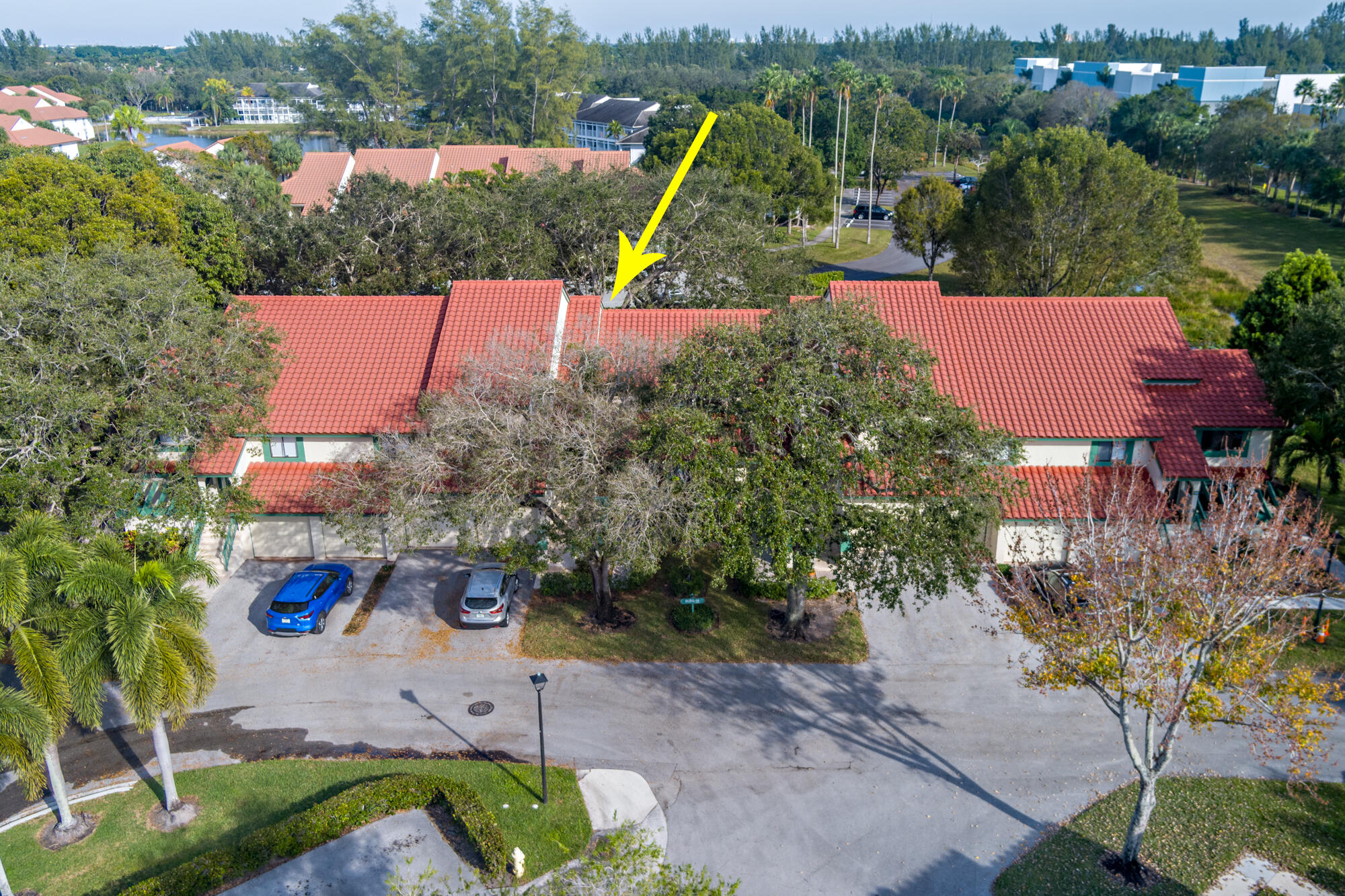 Aerial view of a red-tile-roofed residence, with a yellow arrow marking one unit.