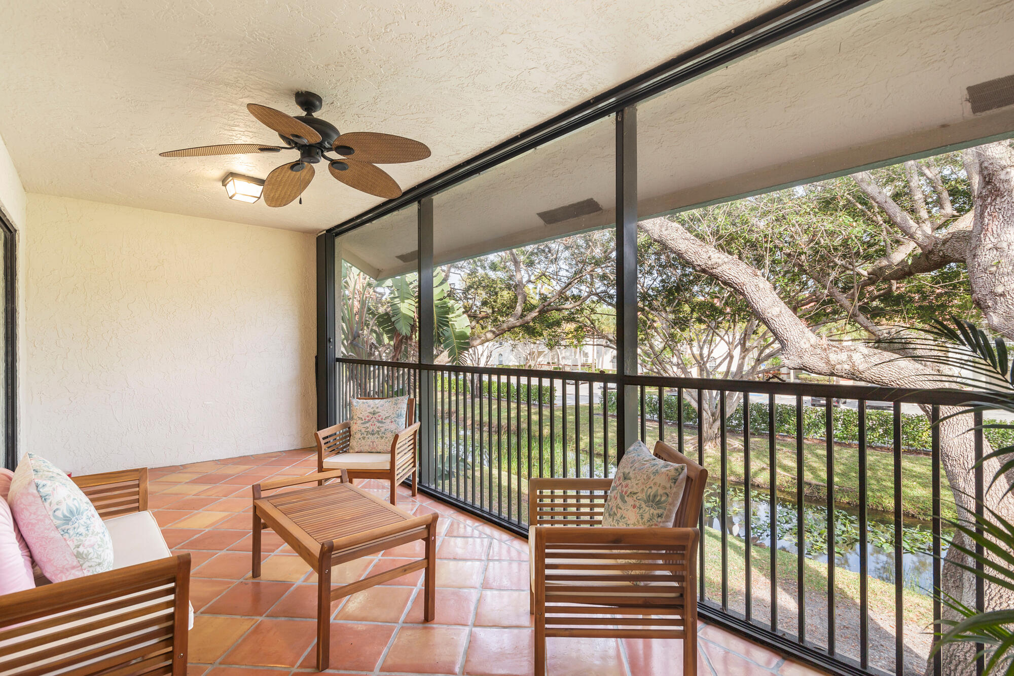 Screened patio with terracotta tile, wooden seating, and leafy garden views.