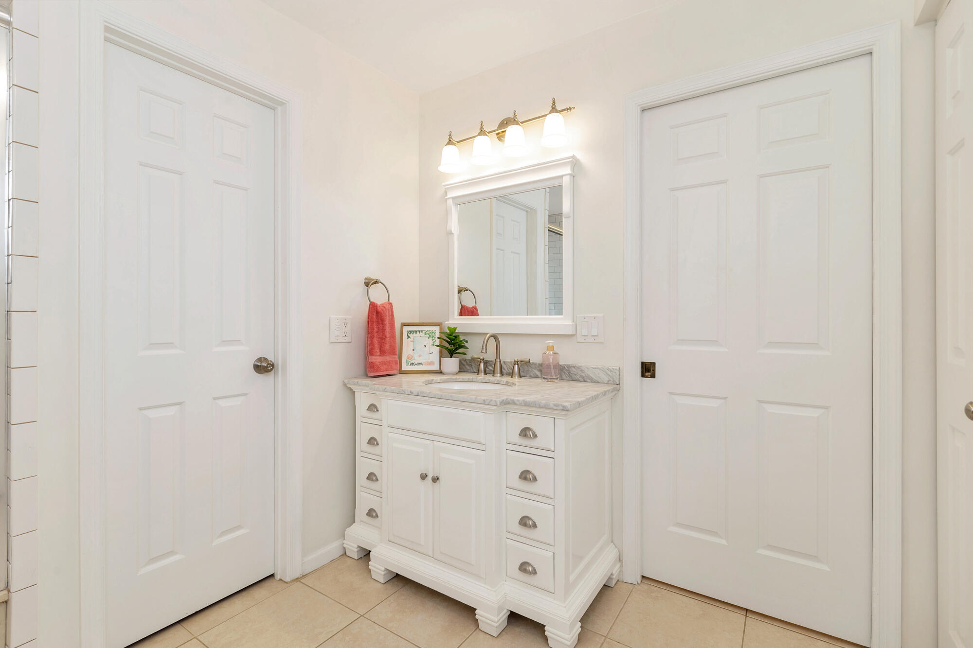 Bathroom vanity with a gray marble countertop, framed mirror, and brass fixtures.