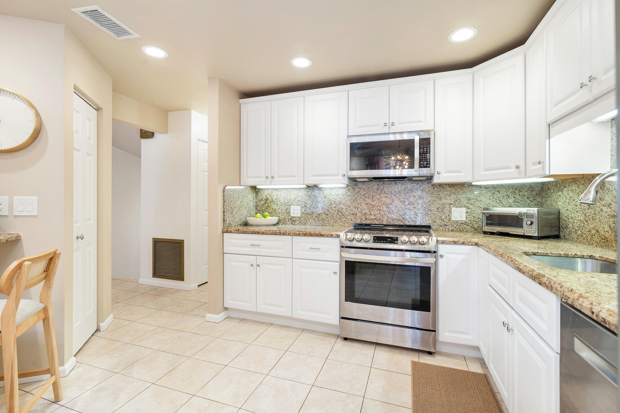 Kitchen with white cabinets, granite counters, and stainless steel range and microwave.