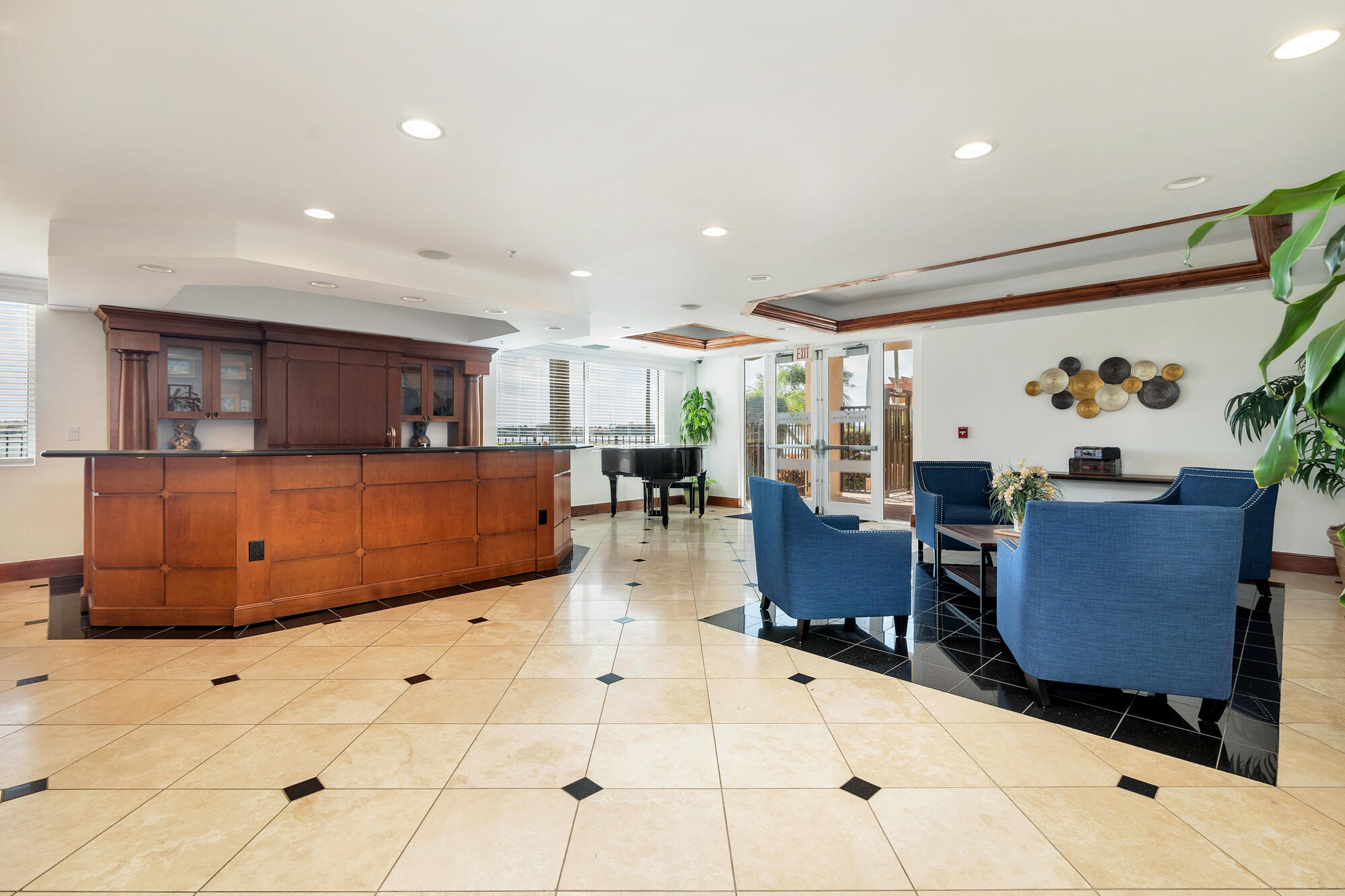 Furnished lounge with a wood-paneled counter, blue armchairs, and a grand piano.