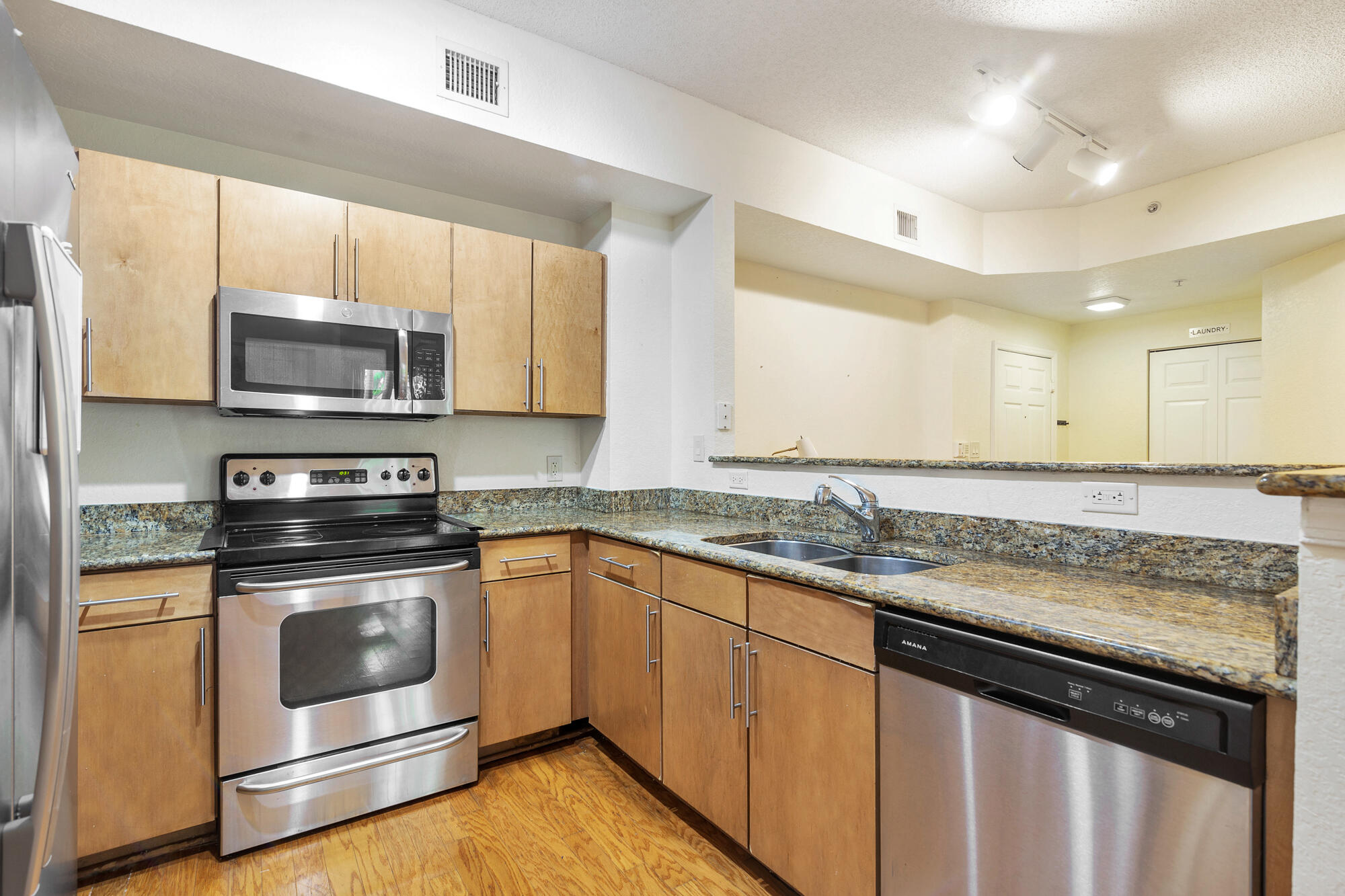 Kitchen with granite counters, light wood cabinets, and stainless steel appliances.