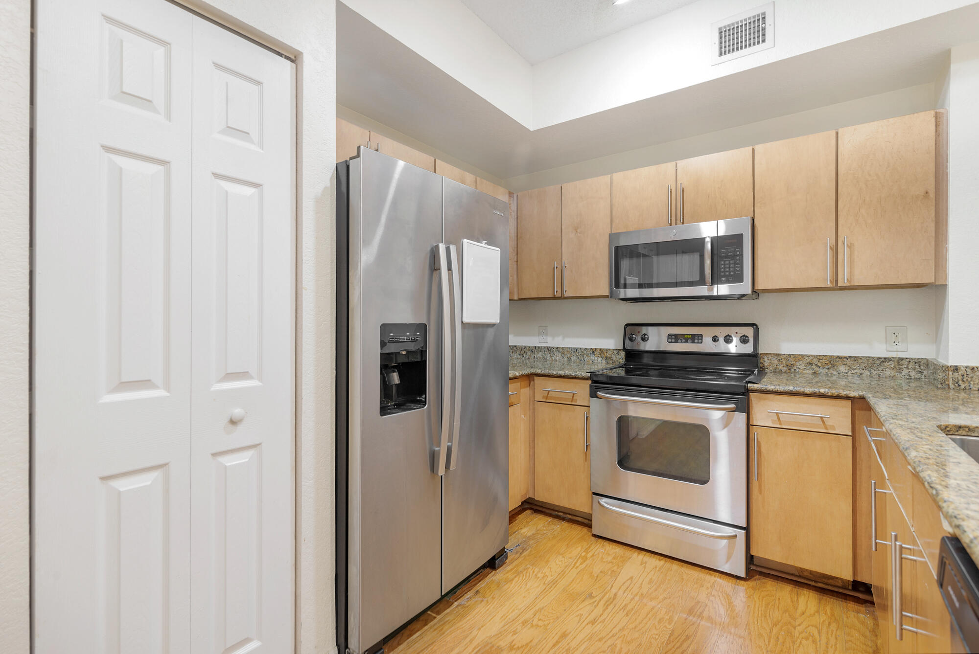 Kitchen with light wood cabinets, granite countertops, and stainless steel appliances.