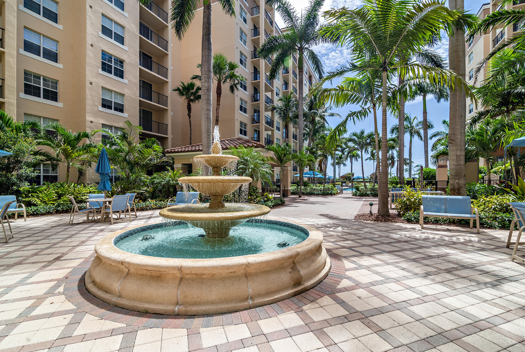 Condominium courtyard with a tiered fountain, palm trees, and paved seating area.
