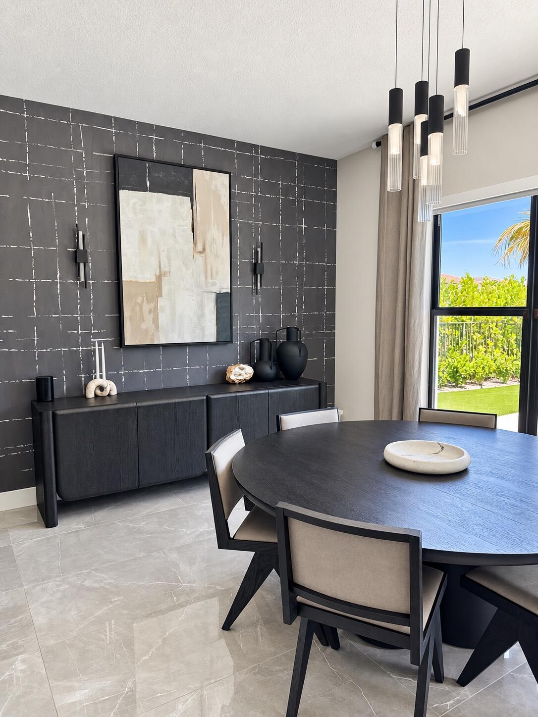 Dining room with a round dark table, charcoal accent wall, and garden-facing window.